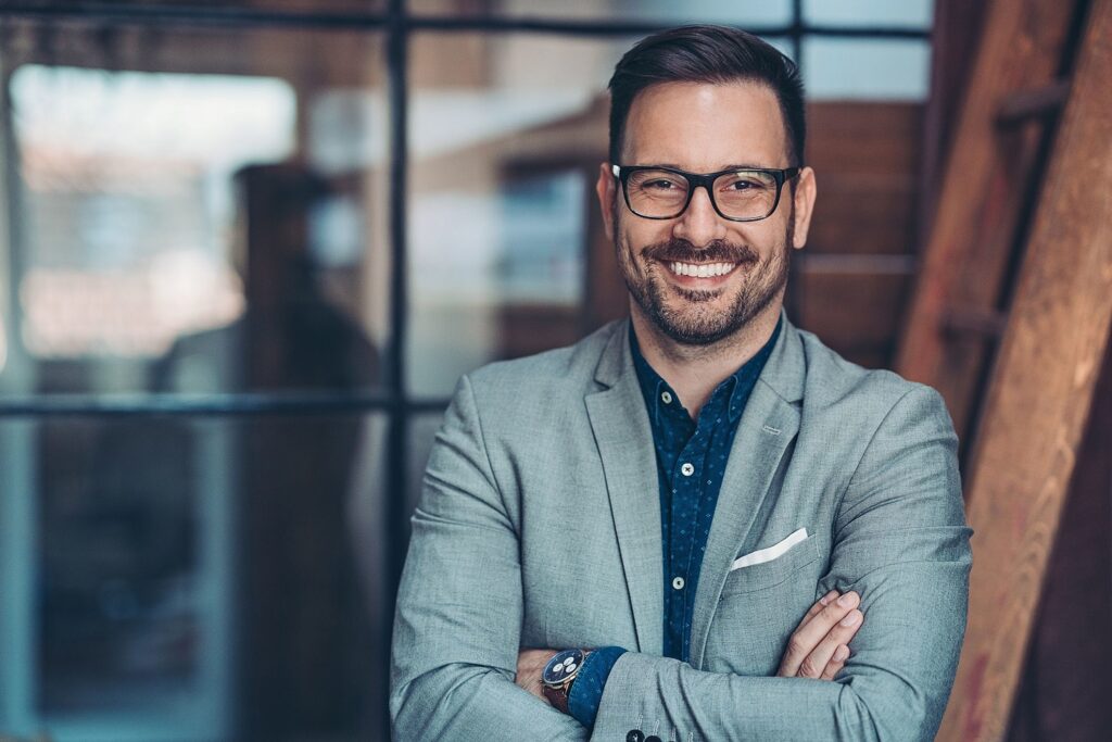 Homem de terno com os braços cruzados e sorrindo