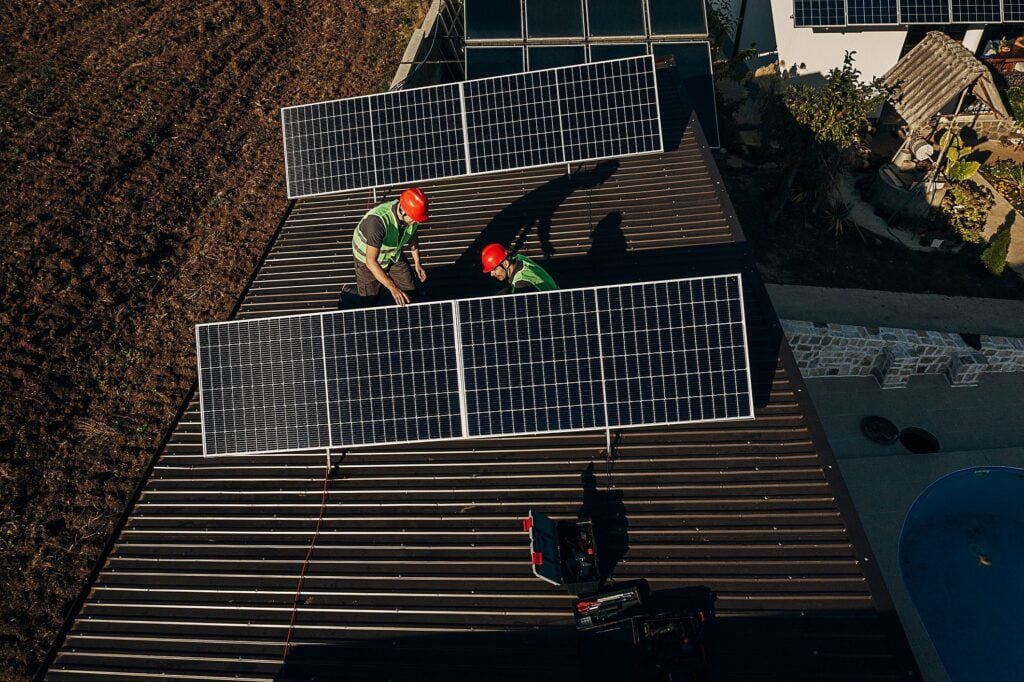Dois homens instalando painéis solares em um telhado