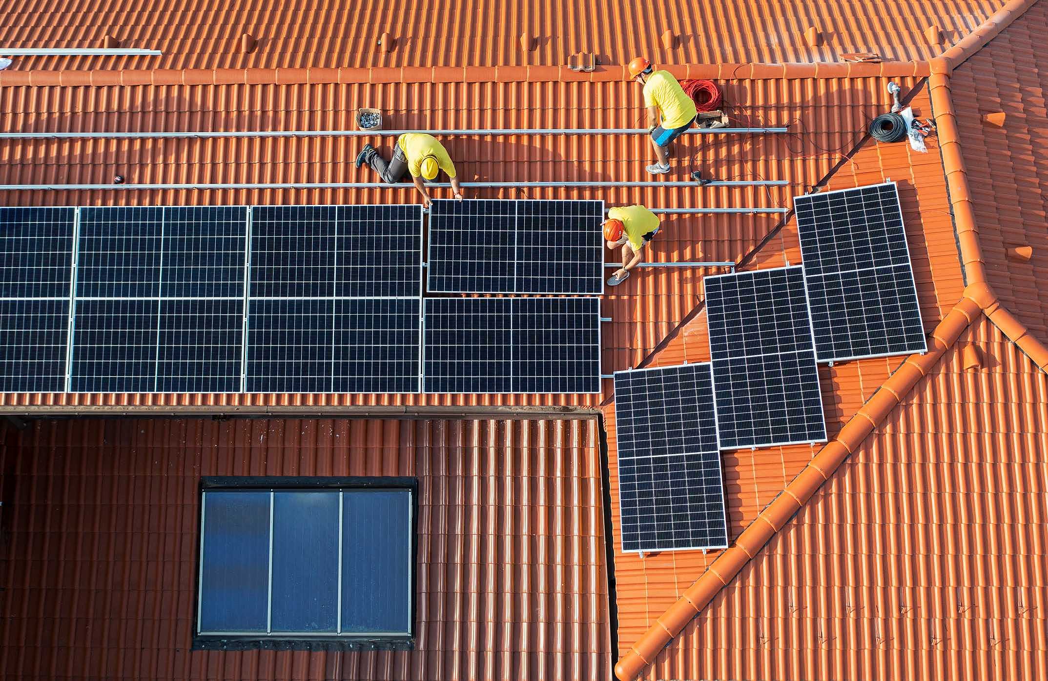vista aérea de telhado com instaladores colocando painéis solares