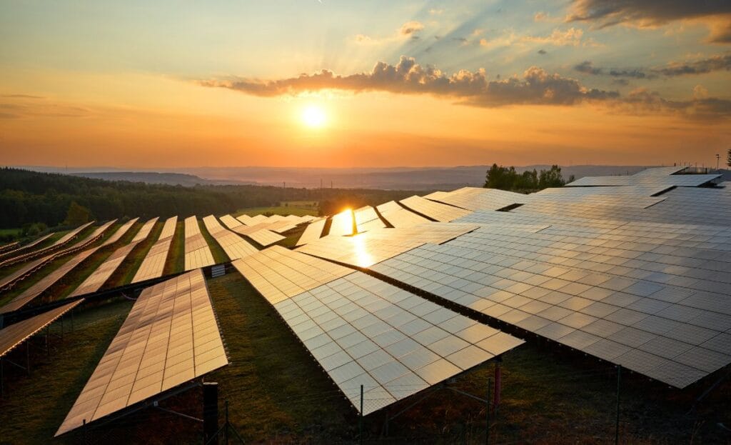 Pôr do sol e uma usina solar de solo com dezenas de painéis solares