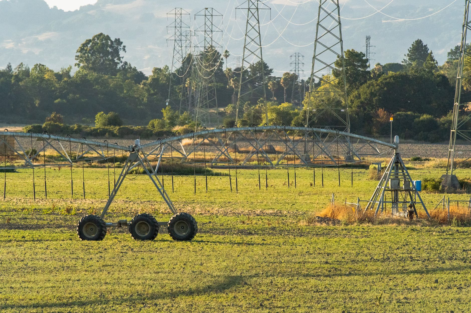 Pivô central de irrigação em lavoura, com linhas de transmissão de energia ao fundo