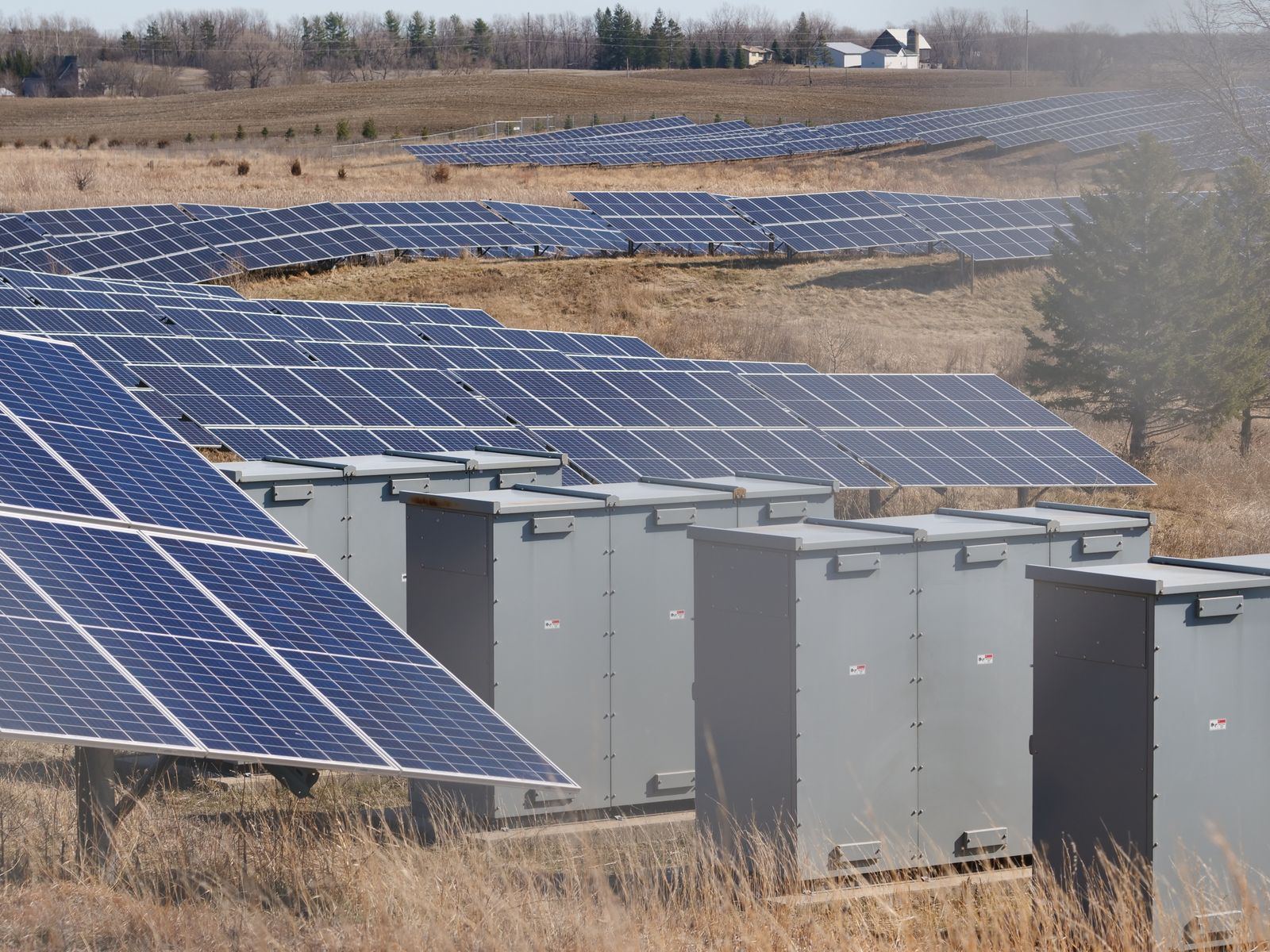 Gabinetes de equipamentos elétricos instalados ao lado de painéis solares em uma usina