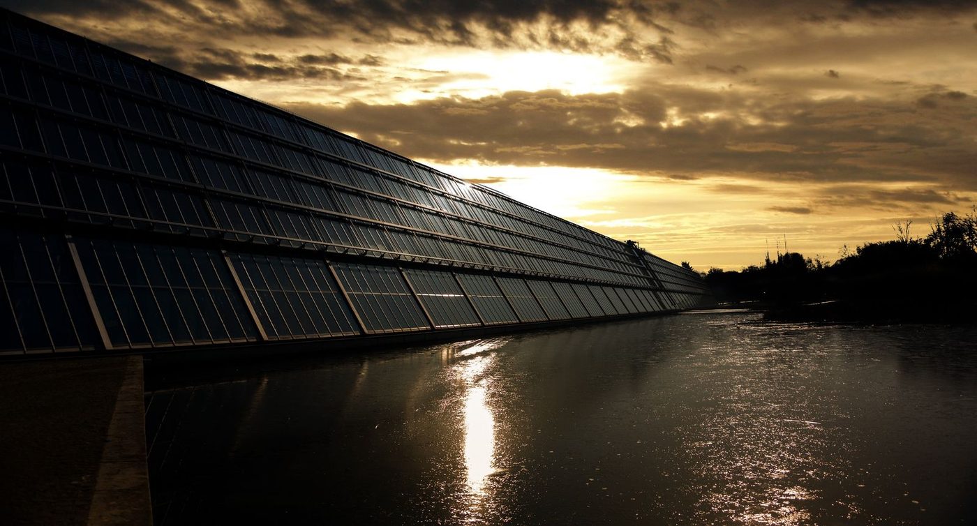 Curva do pato no Brasil Painéis solares em silhueta ao pôr do sol, com reflexo na água