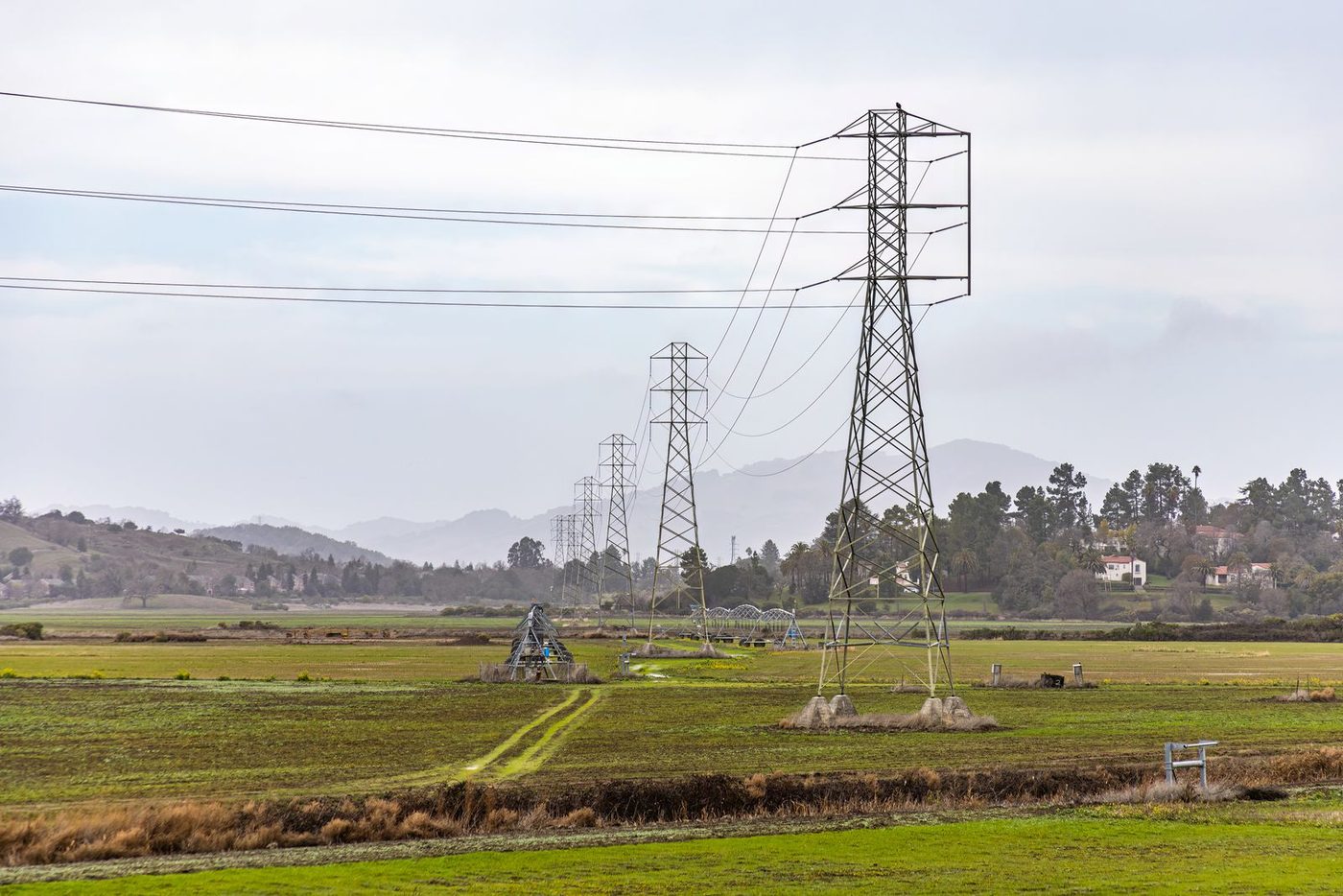 Linhas de transmissão de energia atravessando área agrícola irrigada, com pivô central ao fundo
